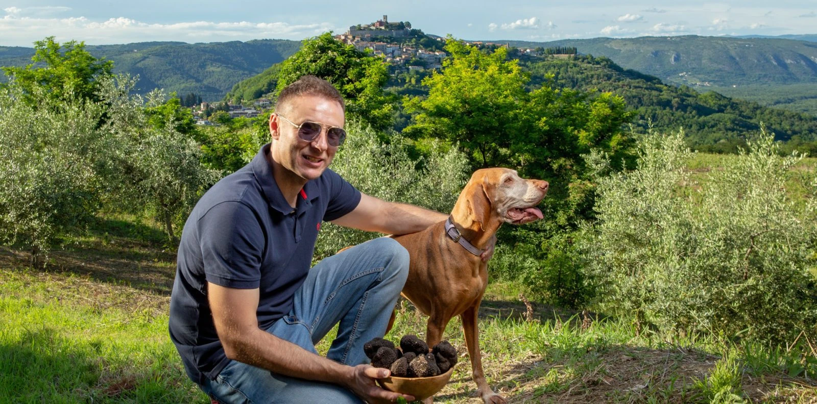 Local Istrian truffle hunting guide with dog and Motovun in the background